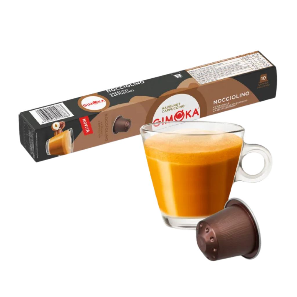 Outin капсула за кафе и чаша с пенлива напитка, разположени на фона на кутия Gimoka Pistacchino.