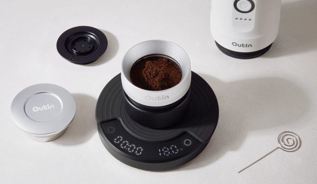 Филтър за кафе Outin със смляно кафе е поставен върху цифрова везна, заобиколен от аксесоари за приготвяне на кафе.