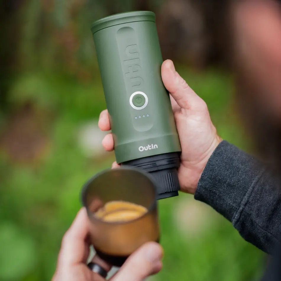 Човек държи зелена преносима кафемашина Outin-перфектен подарък за всеки любител на кафето на открито.